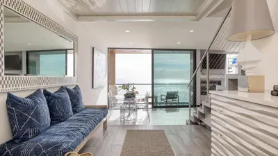a living room with a blue couch and a view of the ocean at Matador by AvantStay Ocean Front Malibu Pad w Rooftop Patio in Topanga