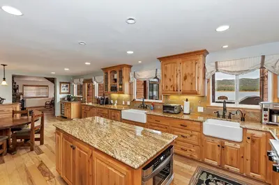 a large kitchen with wooden cabinets and a table at Lakefront Estate w Private Dock HotTub FirePit Lagunita Shores by AvantStay in Big Bear Lake