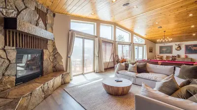 a living room with a stone fireplace and a pool table at Lakefront Lodge by AvantStay Direct Access to Big Bear Lake Hot Tub Views in Big Bear Lake