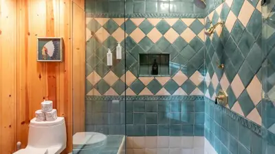 a bathroom with a toilet and a tiled wall at Shoreline Lakehouse by AvantStay Majestic Lakefront Cabin w Hot Tub Fire Pit in Big Bear Lake