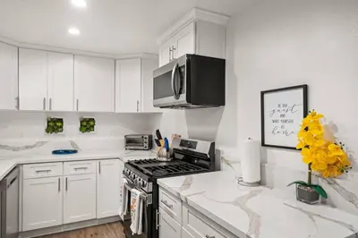 a kitchen with white cabinets and a stove top oven at The Avalon - 35 Percent Off March! in Los Angeles