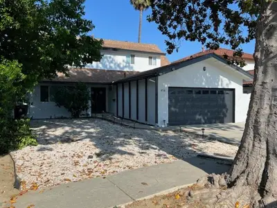 a white house with a garage and a tree at Modern spacious home close to Universal studio & Hollywood for 11 in Los Angeles