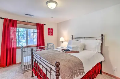 a bedroom with a bed and a window with red curtains at Spacious Lake Arrowhead Home with Putting Green in Lake Arrowhead