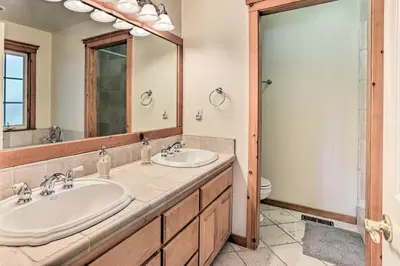 a bathroom with two sinks and a large mirror at Spacious Lake Arrowhead Home with Putting Green in Lake Arrowhead