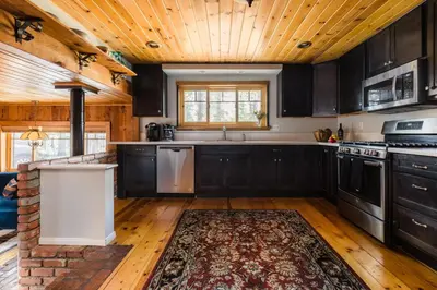 a kitchen with black cabinets and a wooden ceiling at Walk to the Lake Sand Volleyball Court Pool Table Deck Gambler by AvantStay in Big Bear Lake