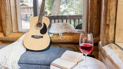 a guitar sitting on a couch next to a glass of wine at Teddy by AvantStay Majestic Cabin in Big Bear w Balcony in Big Bear Lake