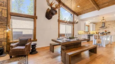 a living room with a table and a kitchen at Teddy by AvantStay Majestic Cabin in Big Bear w Balcony in Big Bear Lake