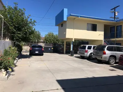 two cars parked in a parking lot in front of a building at King Castle Motel in Los Angeles