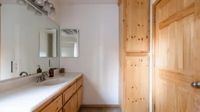 a bathroom with a sink and a mirror and a wooden door at Jackhorn by AvantStay Close to Big Bear Marina and Village Hot Tub Foosball in Big Bear Lake