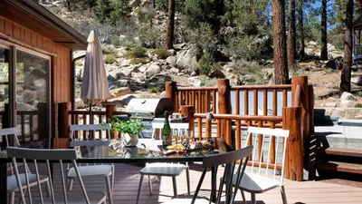 a deck with a table and chairs and an umbrella at Bernard by AvantStay Luxurious Cabin in Big Bear w Hot Tub Pool Table in Big Bear Lake