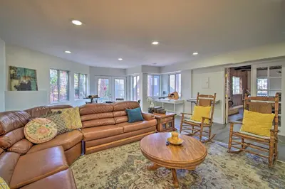 a living room with a brown leather couch and a table at Relaxing Lake Arrowhead Home about 1 Mi to Lake! in Lake Arrowhead