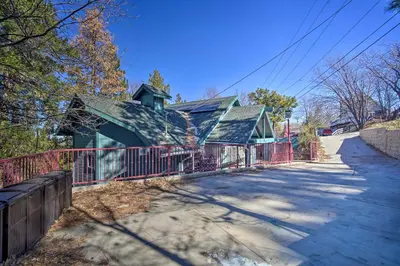 a house with a red fence next to a road at Relaxing Lake Arrowhead Home about 1 Mi to Lake! in Lake Arrowhead