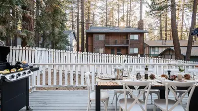 a table and chairs on a deck with a house at Hartwood by AvantStay Cozy Big Bear Abode w Spacious Deck Stone Fireplace in Big Bear Lake