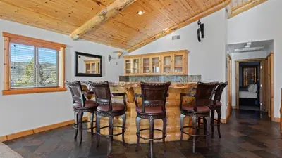 a kitchen with a bar with wooden stools at Starlight Retreat by AvantStay Gorgeous Log Style Home w Incredible Views in Big Bear Lake