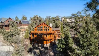 a large wooden house in the middle of trees at Starlight Retreat by AvantStay Gorgeous Log Style Home w Incredible Views in Big Bear Lake