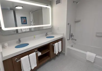 a bathroom with two sinks and a large mirror at Howard Johnson by Wyndham Anaheim Hotel and Water Playground in Anaheim