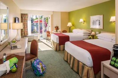 a hotel room with two beds and a desk at Howard Johnson by Wyndham Anaheim Hotel and Water Playground in Anaheim