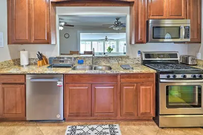 a kitchen with wooden cabinets and stainless steel appliances at Quiet Anaheim Home with Pool, 5 Mi to Disney! in Anaheim