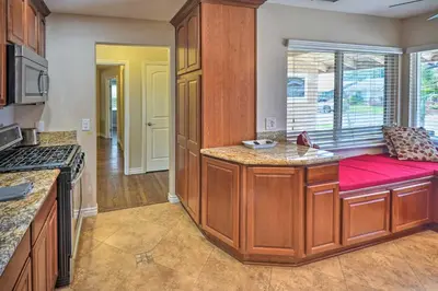 a kitchen with wooden cabinets and a red bench at Quiet Anaheim Home with Pool, 5 Mi to Disney! in Anaheim