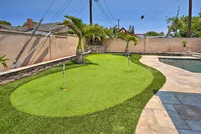 a green yard with palm trees and a pool at Quiet Anaheim Home with Pool, 5 Mi to Disney! in Anaheim