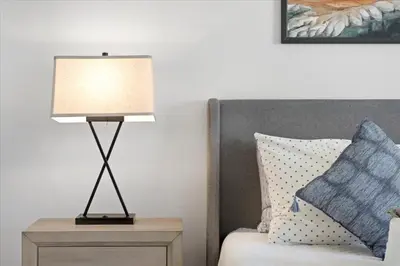 a lamp on a night stand next to a bed at Revitalizing 3 Bedroom Home With Pool, Pet-Friendly, Wi-fi in Bakersfield