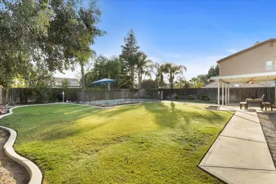 a large yard with a bench and a fence at Revitalizing 3 Bedroom Home With Pool, Pet-Friendly, Wi-fi in Bakersfield