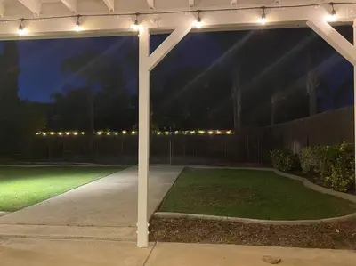 a pergola with lights on a lawn at night at Revitalizing 3 Bedroom Home With Pool, Pet-Friendly, Wi-fi in Bakersfield