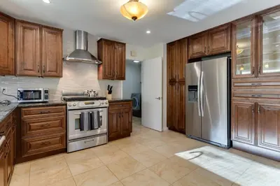 a kitchen with wooden cabinets and a stainless steel refrigerator at 4 Bedroom West Hills Charmer with Pool and Jacuzzi in Los Angeles
