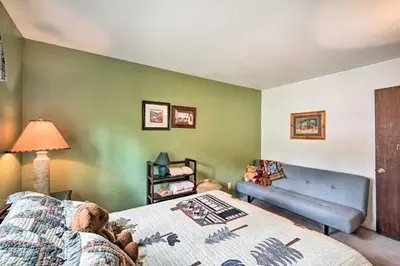 a bedroom with a bed and a blue couch at 3 Mi to Skiing Big Bear Cabin with Deck in Big Bear City