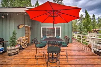 a patio with a table with a red umbrella at 3 Mi to Skiing Big Bear Cabin with Deck in Big Bear City