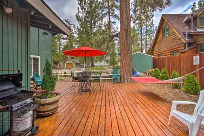 a wooden deck with a table and an umbrella at 3 Mi to Skiing Big Bear Cabin with Deck in Big Bear City