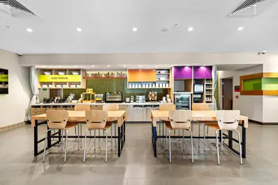 a kitchen with wooden tables and chairs and a counter at Home2 Suites By Hilton San Bernardino in San Bernardino