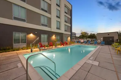 a swimming pool with chairs and a building at Home2 Suites By Hilton San Bernardino in San Bernardino