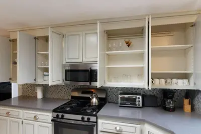 a kitchen with white cabinets and a stove and microwave at Woodland Hills Charmer in Los Angeles