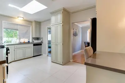 a kitchen with white cabinets and a white tile floor at Woodland Hills Charmer in Los Angeles