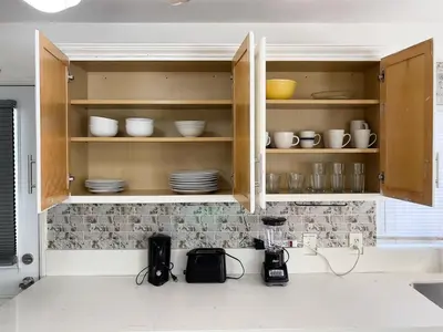 a kitchen with wooden cabinets with plates and bowls at 3 bedroom Mid-Wilshire Charmer near Downtown in Los Angeles