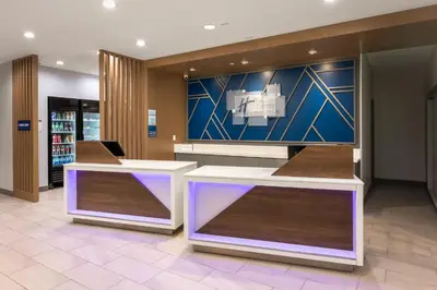 a lobby with two white tables and a blue wall at Holiday Inn Express & Suites Hawaiian Gardens by IHG in Hawaiian Gardens