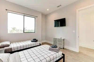 a bedroom with two beds and a tv on the wall at 3 Luxury Modern Homes 12 bedrooms & Rooftop Decks in Los Angeles