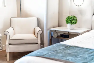 a bedroom with a chair and a plant on a table at Aspire Inn Studios & Spas in Bellflower