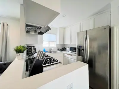 a kitchen with white cabinets and a stainless steel refrigerator at Hollywood Purple Habitat in Los Angeles