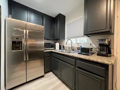 a kitchen with black cabinets and a stainless steel refrigerator at Hollywood Black Habitat in Los Angeles