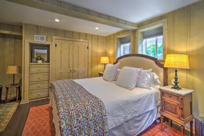 a bedroom with a bed and a table with a lamp at Vintage Lake Arrowhead Cabin - Walk to Lake! in Lake Arrowhead