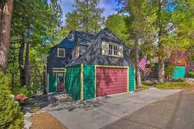 a house with a garage and an american flag at Vintage Lake Arrowhead Cabin - Walk to Lake! in Lake Arrowhead