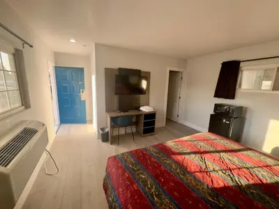 a bedroom with a bed and a desk and a television at Keystone Motel in Norwalk