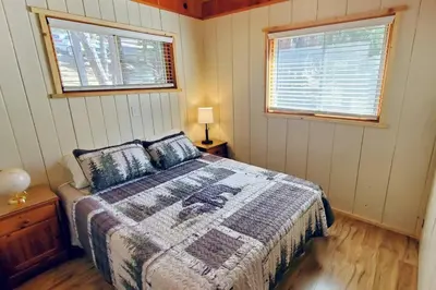 a bedroom with a bed and two windows at Redwood Retreat, Mountains, Adventure and Nature in Ponderosa