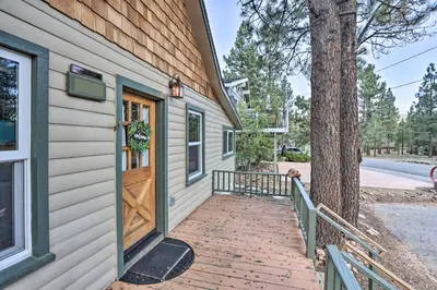 a house with a wooden door next to a tree at Walk to Big Bear Lake Cozy Cabin with Deck in Big Bear Lake