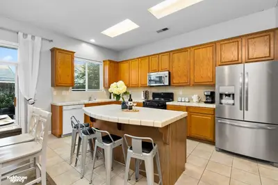 a kitchen with wooden cabinets and a kitchen island with chairs at NorthWest Farmhouse in Bakersfield