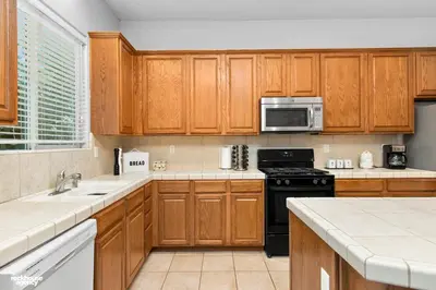 a kitchen with wooden cabinets and a black stove top oven at NorthWest Farmhouse in Bakersfield