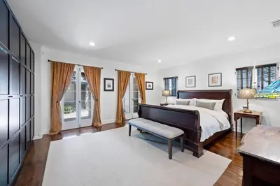 a bedroom with a bed and a bench and windows at Secluded 4BR Spanish Oasis in the Heart of LA in Los Angeles