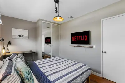 a bedroom with a bed and a tv on the wall at Beach Villa * Hot Tub * Steps to Beach in Long Beach